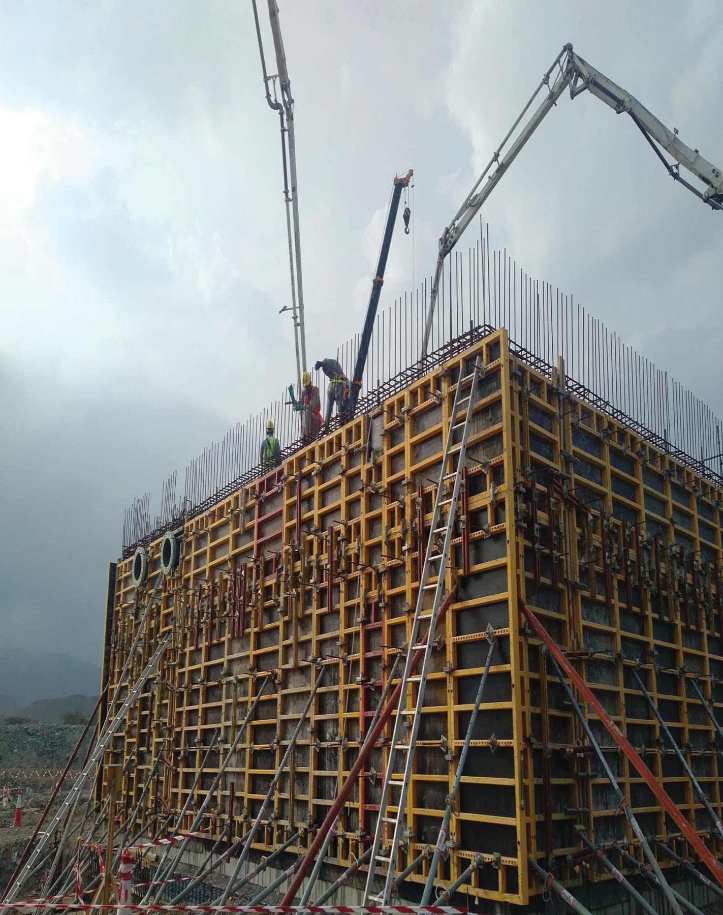 Concrete boom pump casting the walls of a balancing tank with yellow formwork at Kalba sewage treatment plant