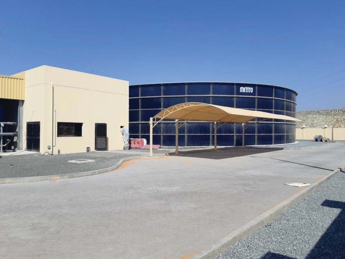 Completed MCC building beside shaded glass-fused-to-steel tanks at the Kalba sewage treatment plant